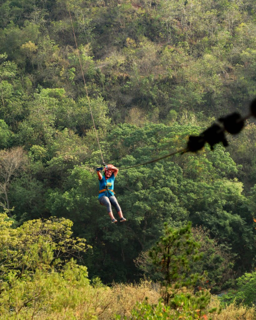 Una señora cruzando la tirolesa con determinación, superando su miedo y disfrutando de la experiencia.