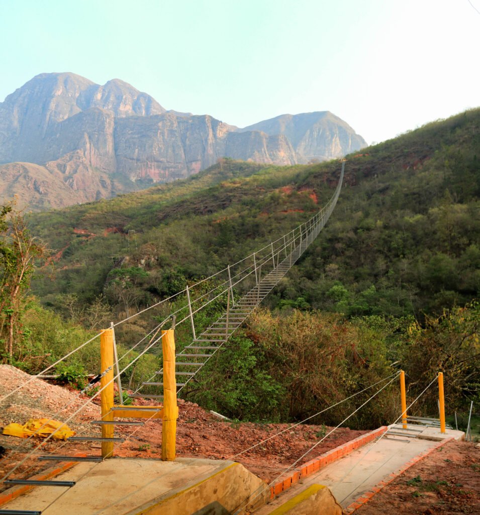 Vista de la escalera colgante extendiéndose hacia el final del tramo, rodeada de naturaleza y aventura.