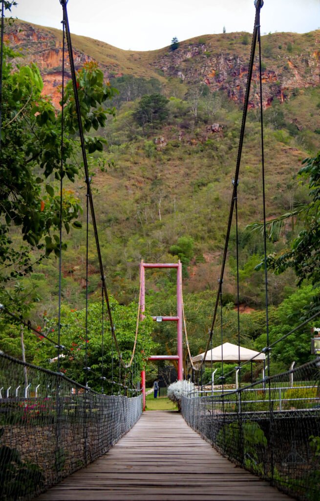Un puente rústico que cruza sobre un río cristalino, camino al Restaurante El Encanto.