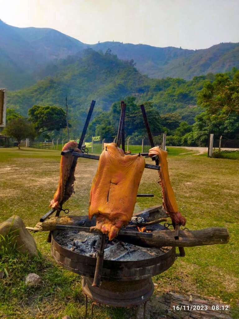 Preparación del chancho a la cruz, con carne de cerdo asada lentamente sobre fuego abierto.
