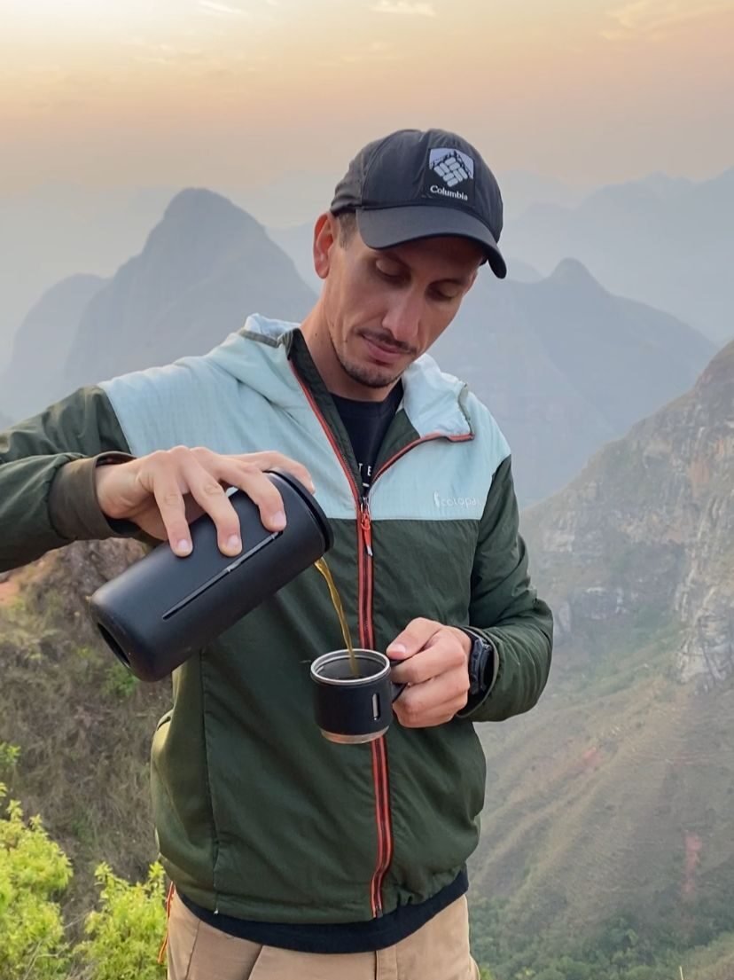 Andrés preparando café en la montaña con una increíble vista al amanecer.